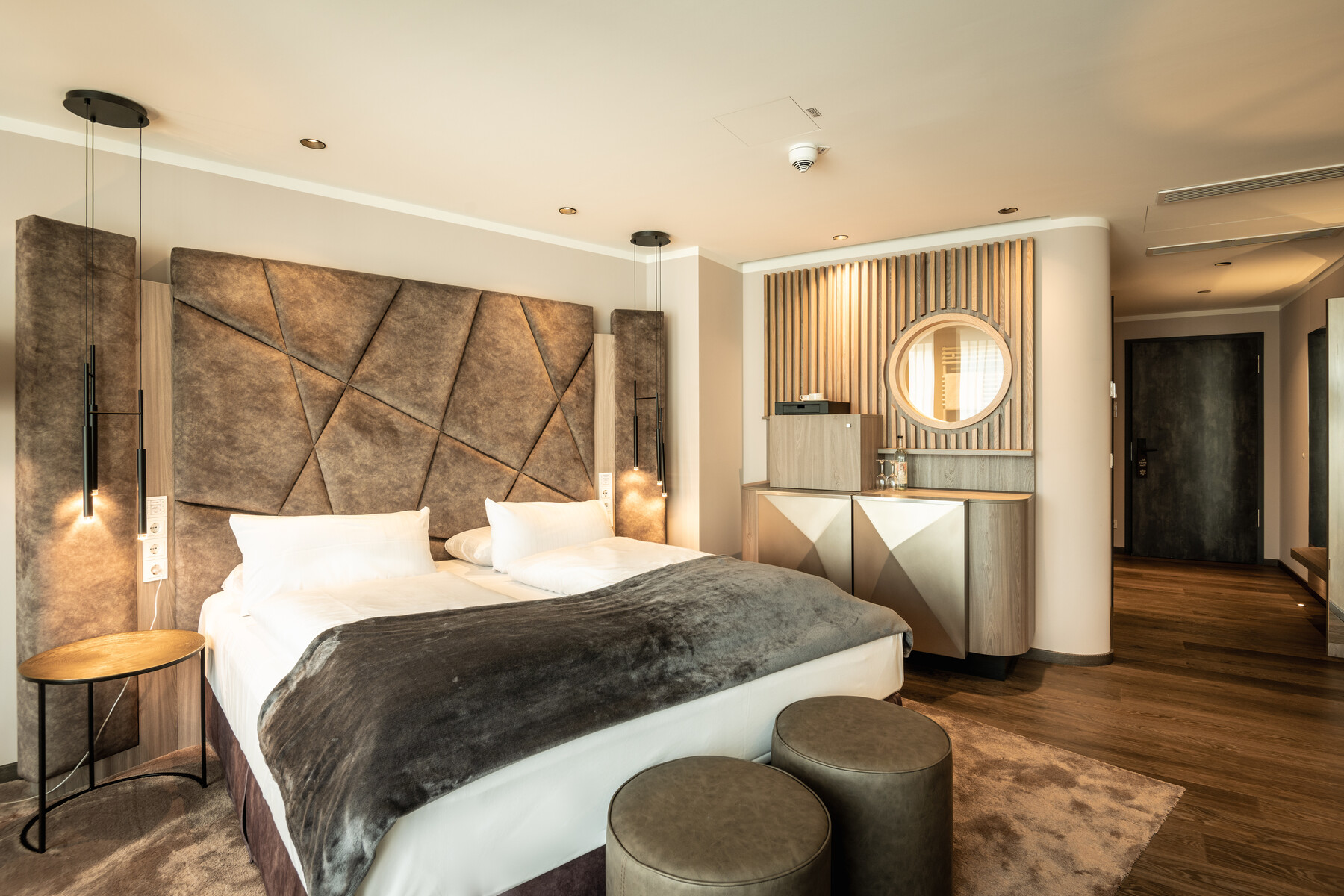 Junior Suite Detail: Schlafbereich, Doppelbett mit Kopfteil, warme Farbtöne