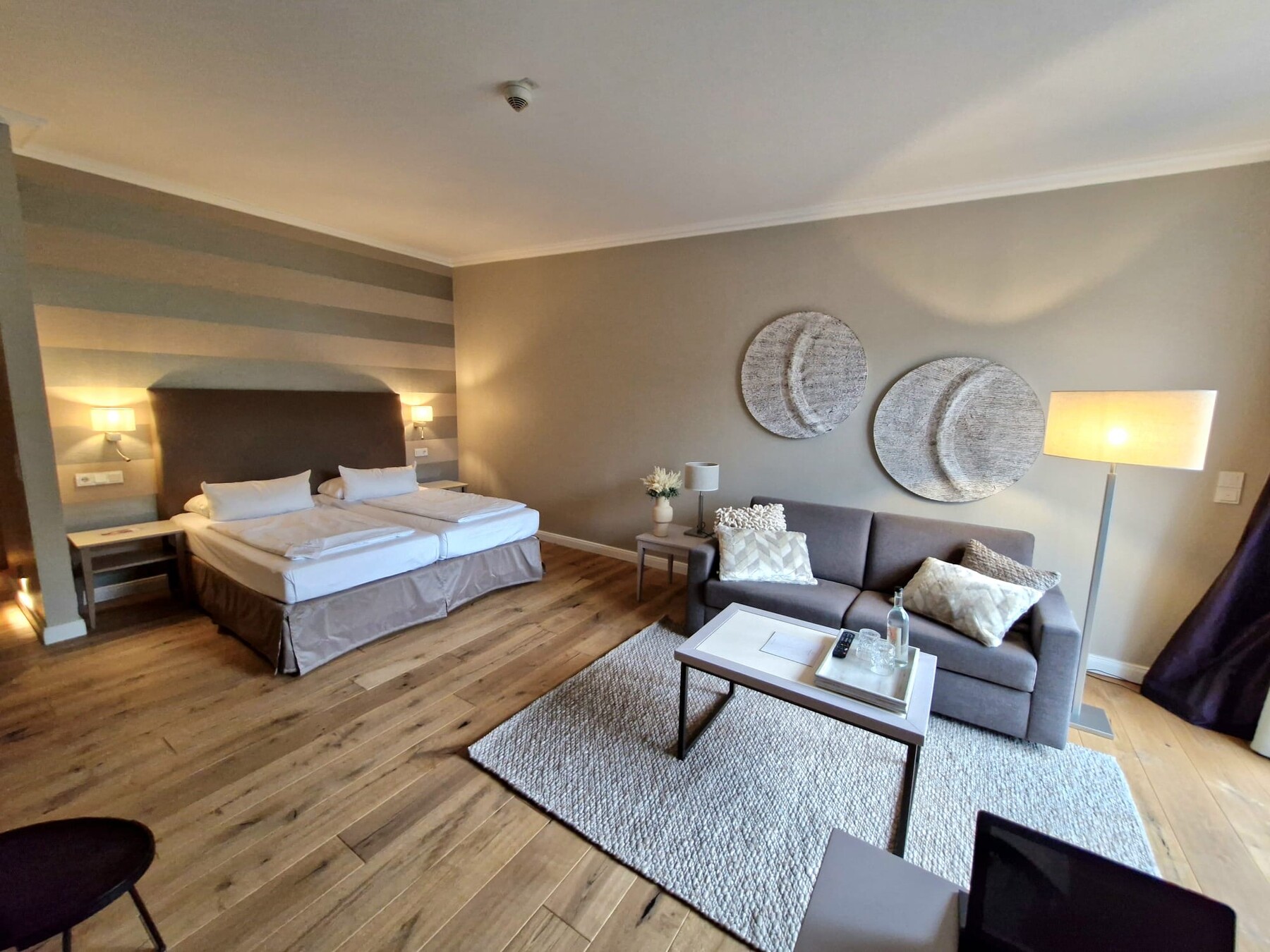 Zimmerdetail: cremefarbene Wand, Holzvertäfelung, dezente Beleuchtung, moderne Inneneinrichtung